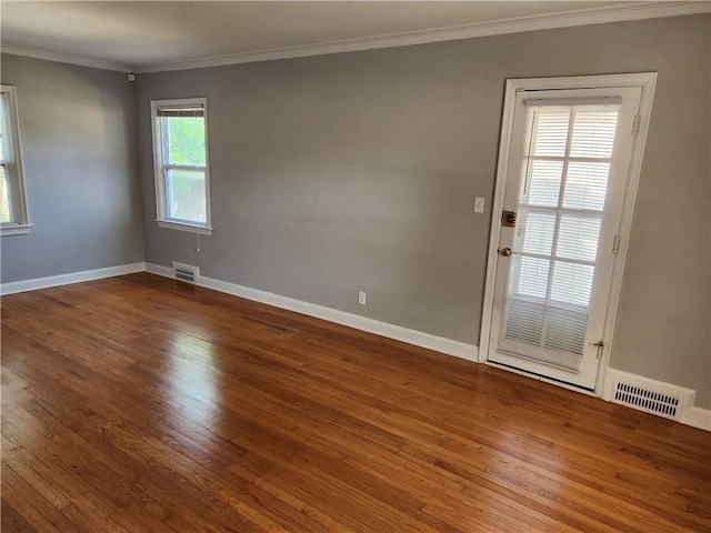 spare room featuring wood-type flooring, crown molding, and baseboards