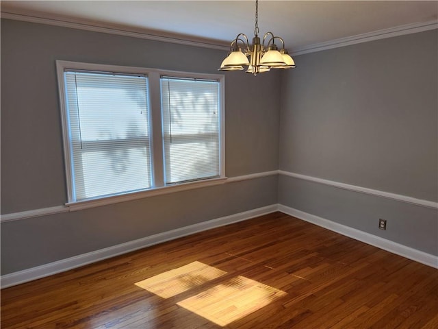 spare room with a chandelier, dark wood-style floors, crown molding, and baseboards