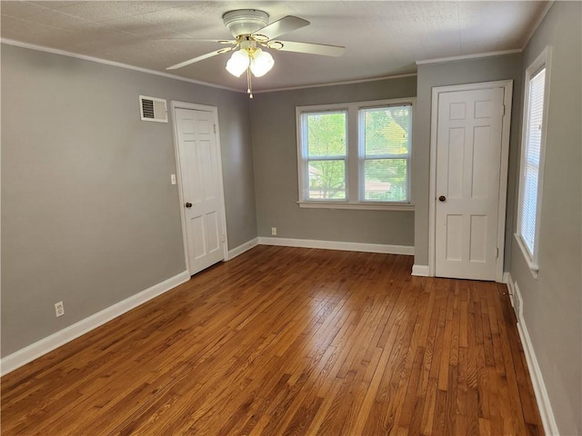 unfurnished room with crown molding, hardwood / wood-style flooring, a ceiling fan, and baseboards