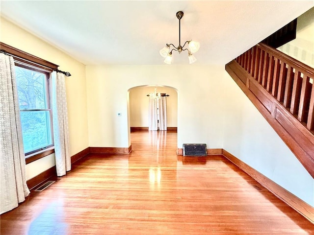 1420 N Mulberry St, Maryville, MO 64468 - empty room featuring a chandelier, arched walkways, light wood finished floors, and baseboards