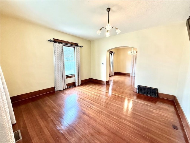 1420 N Mulberry St, Maryville, MO 64468 - spare room featuring arched walkways, a chandelier, wood finished floors, and baseboards