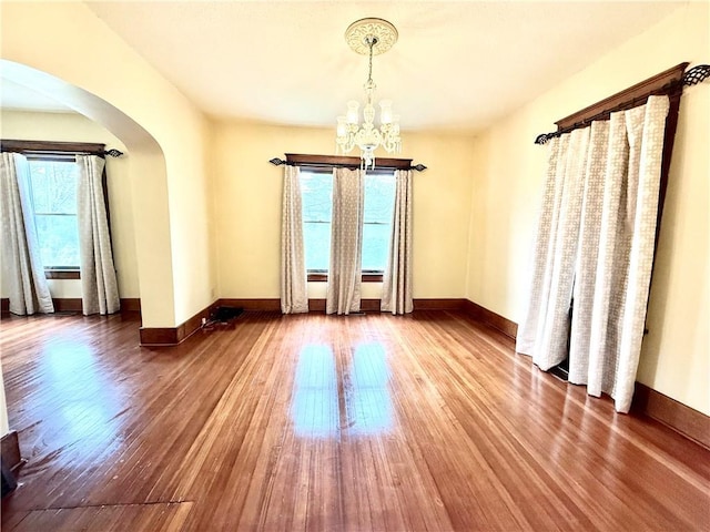 1420 N Mulberry St, Maryville, MO 64468 - spare room with arched walkways, wood finished floors, a chandelier, and baseboards