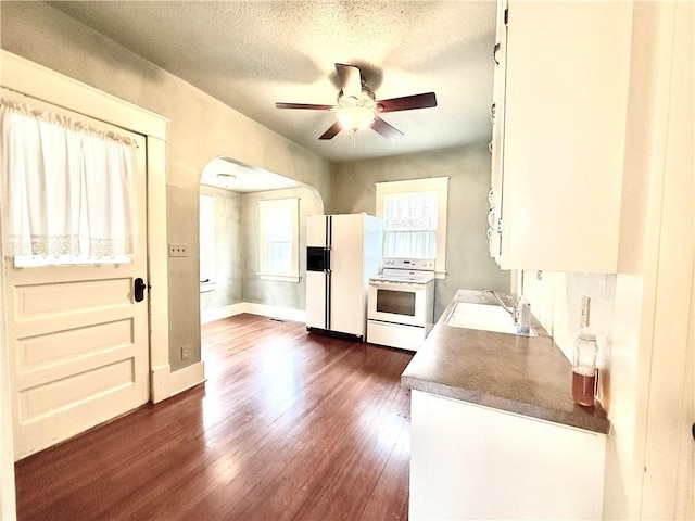 1420 N Mulberry St, Maryville, MO 64468 - kitchen with a sink, white appliances, a ceiling fan, arched walkways, and dark wood finished floors