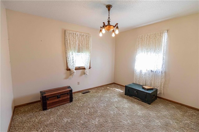 802 Cherry St, Lamar, MO 64759 - empty room with a textured ceiling, visible vents, carpet floors, baseboards, and a chandelier