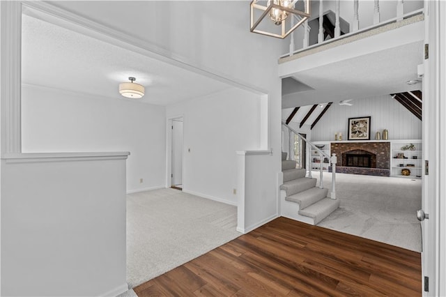 entrance foyer featuring wood finished floors, stairs, a chandelier, a fireplace, and baseboards