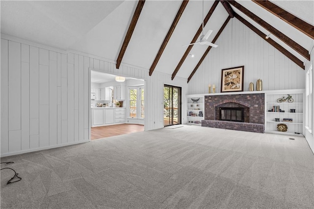 unfurnished living room featuring beamed ceiling, wood walls, and carpet