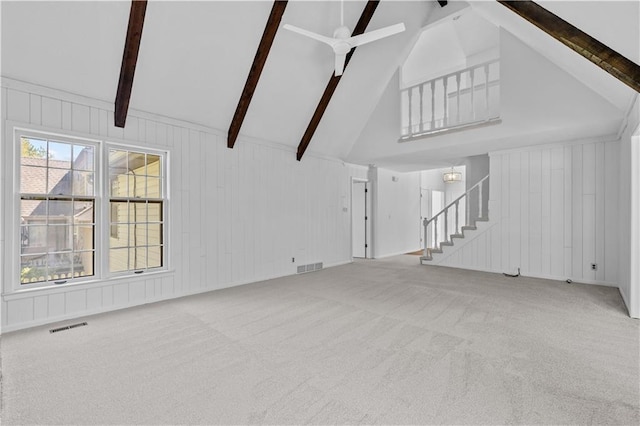 unfurnished living room featuring carpet flooring, beamed ceiling, visible vents, ceiling fan, and stairs