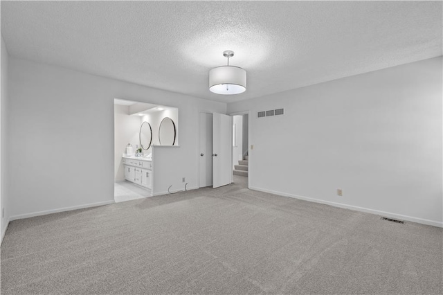 unfurnished bedroom with a textured ceiling, visible vents, and carpet floors