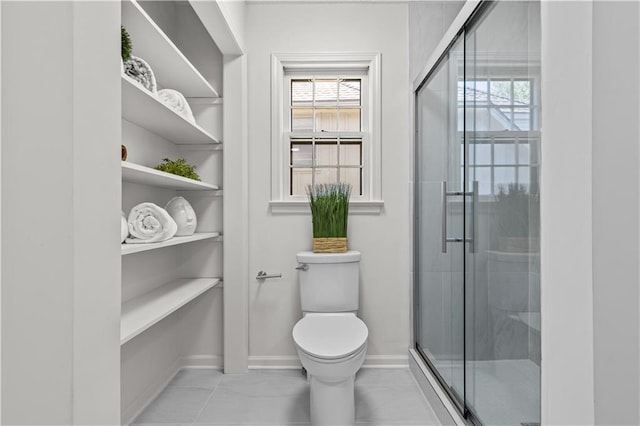 bathroom with toilet, a stall shower, baseboards, and plenty of natural light
