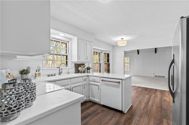 kitchen with a textured ceiling, a sink, white dishwasher, freestanding refrigerator, and a peninsula