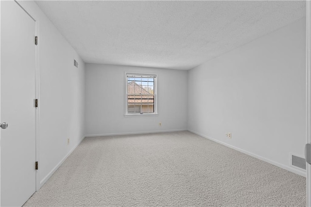spare room with baseboards, visible vents, a textured ceiling, and light colored carpet