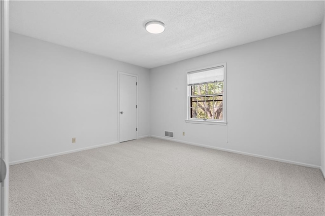 empty room with a textured ceiling, visible vents, carpet flooring, and baseboards