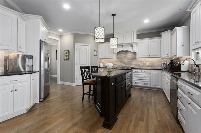 kitchen featuring a sink, stainless steel appliances, a kitchen bar, baseboards, and white cabinets
