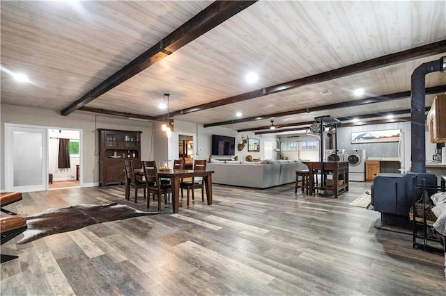 11155 Hubbard Rd, Kansas City, KS 66109 - dining space with a wood stove, beam ceiling, wood finished floors, baseboards, and washer and clothes dryer