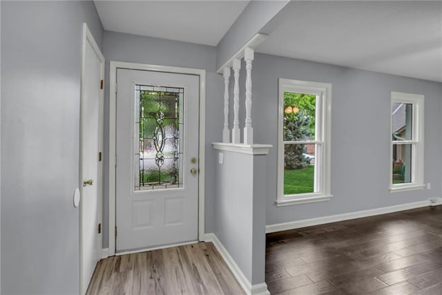 doorway featuring baseboards, a wealth of natural light, and wood finished floors