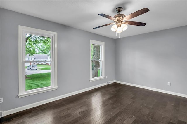 spare room featuring baseboards, dark wood finished floors, and ceiling fan