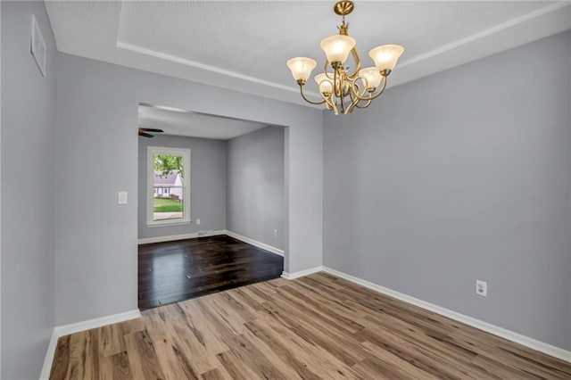 empty room featuring baseboards, a chandelier, and wood finished floors