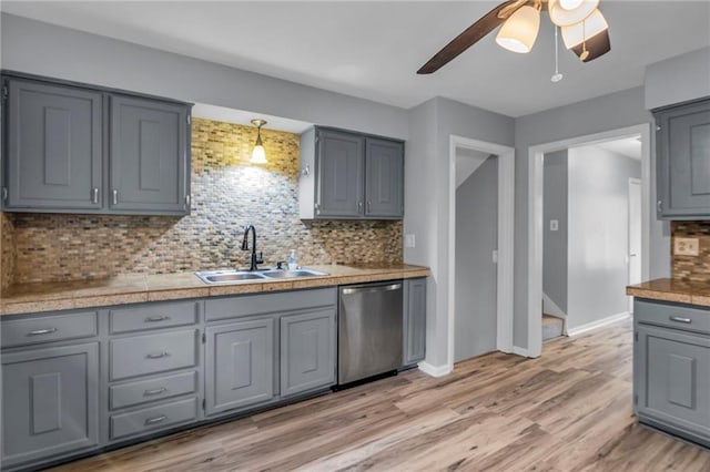 kitchen with gray cabinets, ceiling fan, tasteful backsplash, stainless steel dishwasher, and a sink