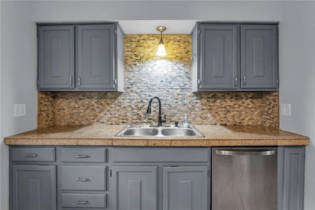 kitchen with gray cabinets, tile countertops, a sink, and dishwasher