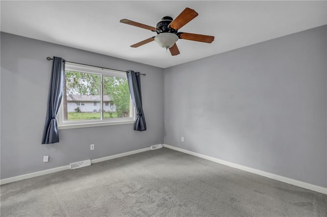 carpeted empty room with ceiling fan, visible vents, and baseboards