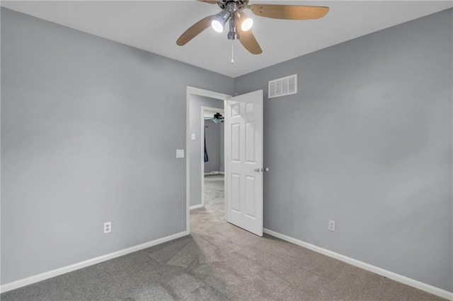 carpeted empty room with baseboards, a ceiling fan, and visible vents