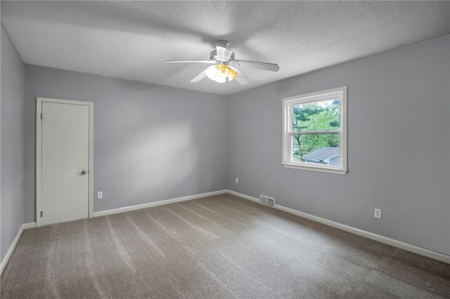 carpeted spare room with baseboards, a ceiling fan, a textured ceiling, and visible vents