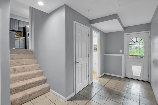 entryway with baseboards, stairs, and light tile patterned flooring