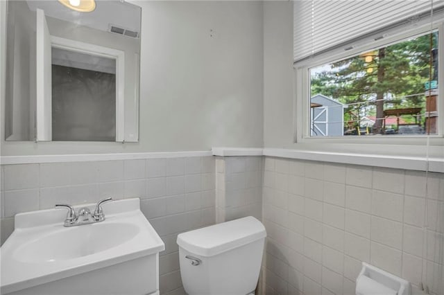 half bath featuring a sink, tile walls, and toilet