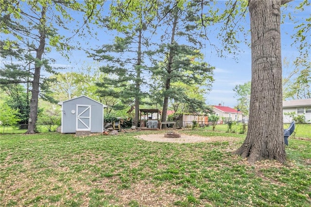 view of yard featuring a storage unit, an outdoor fire pit, fence, and an outbuilding
