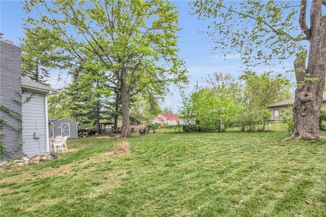 view of yard featuring a storage unit, fence, and an outbuilding