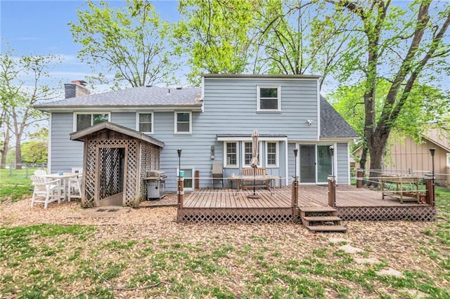 rear view of property featuring fence, a shingled roof, and a deck