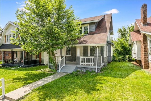2219 E Meyer Blvd, Kansas City, MO 64132 - view of front facade featuring covered porch, a front lawn, and a shingled roof