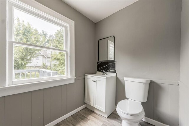 2219 E Meyer Blvd, Kansas City, MO 64132 - bathroom with vanity, toilet, wood finished floors, wainscoting, and a decorative wall