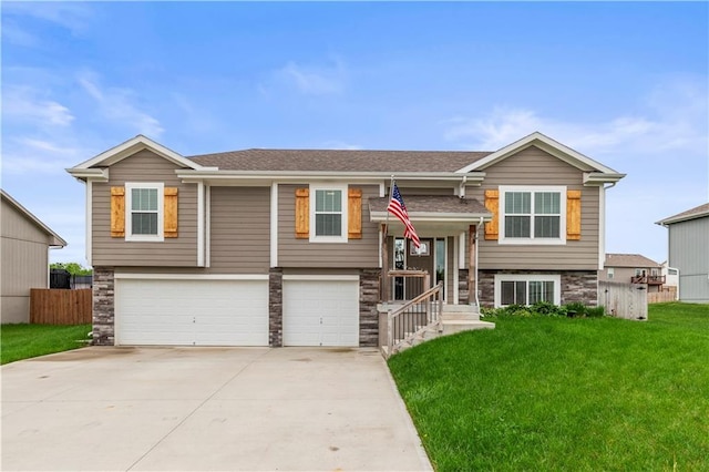 split foyer home featuring fence, an attached garage, concrete driveway, a front lawn, and a shingled roof