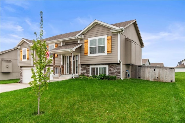 split foyer home featuring driveway, a front lawn, stone siding, and fence