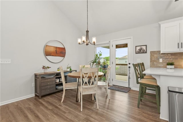 dining space with baseboards, an inviting chandelier, high vaulted ceiling, and wood finished floors