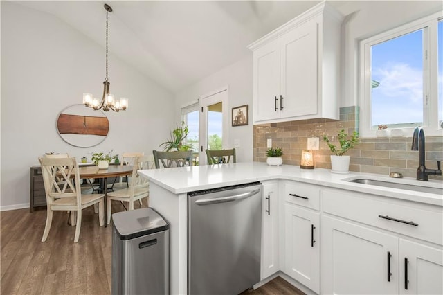 kitchen with an inviting chandelier, a sink, stainless steel dishwasher, backsplash, and lofted ceiling