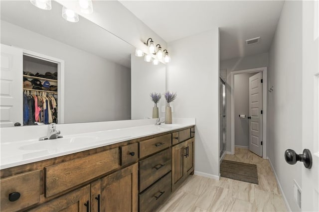 bathroom featuring double vanity, a stall shower, a sink, visible vents, and a spacious closet