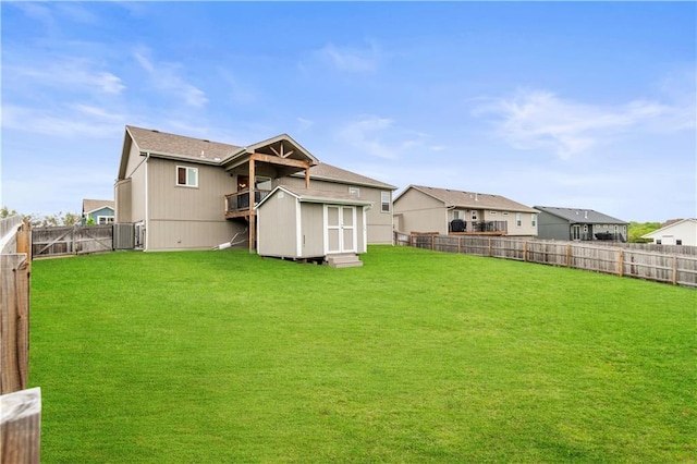 rear view of house featuring a yard, an outbuilding, a fenced backyard, and a shed