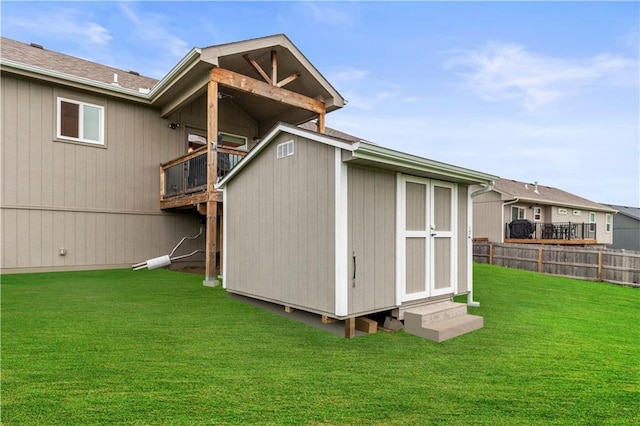 rear view of house with a yard, fence, an outdoor structure, entry steps, and a storage shed