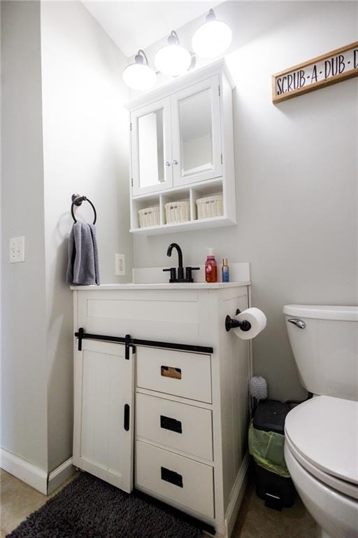 bathroom with baseboards, toilet, and vanity