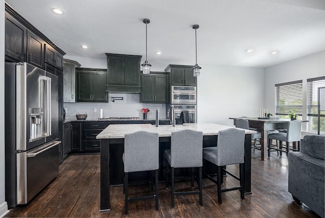 kitchen with light stone counters, stainless steel appliances, pendant lighting, decorative backsplash, and dark wood-style flooring
