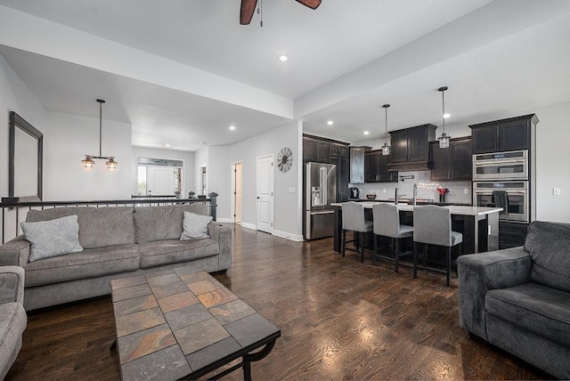 living room with dark wood-type flooring, a ceiling fan, baseboards, and recessed lighting