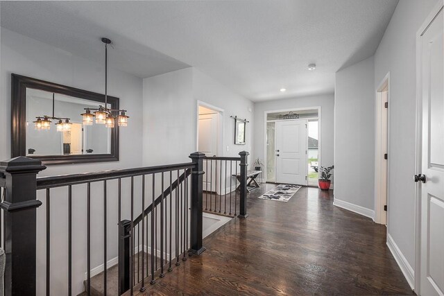 hallway with baseboards, wood finished floors, an upstairs landing, and recessed lighting