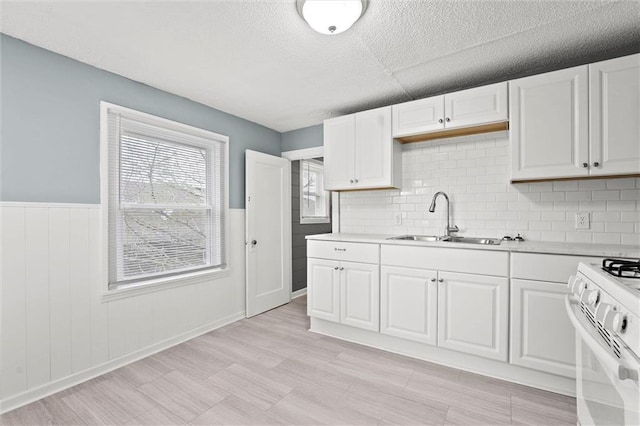 510 E Park St, Olathe, KS 66061 - kitchen with white gas stove, light countertops, a textured ceiling, white cabinets, and a wainscoted wall