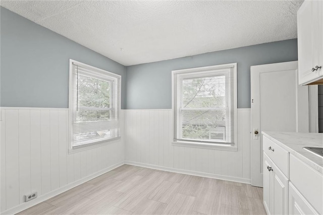510 E Park St, Olathe, KS 66061 - unfurnished dining area with wainscoting, a textured ceiling, and light wood-type flooring