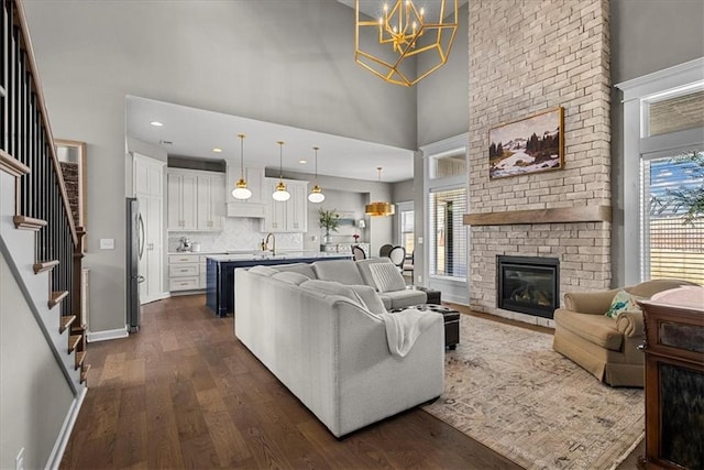 21410 W 189th Ter, Spring Hill, KS 66083 - living room with a towering ceiling, a chandelier, dark wood finished floors, plenty of natural light, and a brick fireplace