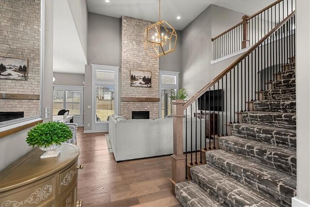 21410 W 189th Ter, Spring Hill, KS 66083 - living room featuring a brick fireplace, a towering ceiling, stairs, wood finished floors, and a chandelier