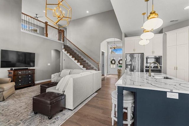 21410 W 189th Ter, Spring Hill, KS 66083 - living room with a high ceiling, dark wood-type flooring, arched walkways, a chandelier, and stairway