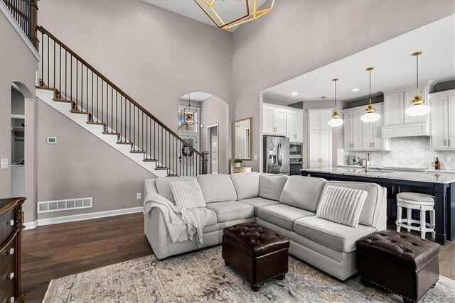 21410 W 189th Ter, Spring Hill, KS 66083 - living area featuring stairs, wood finished floors, a high ceiling, a chandelier, and arched walkways